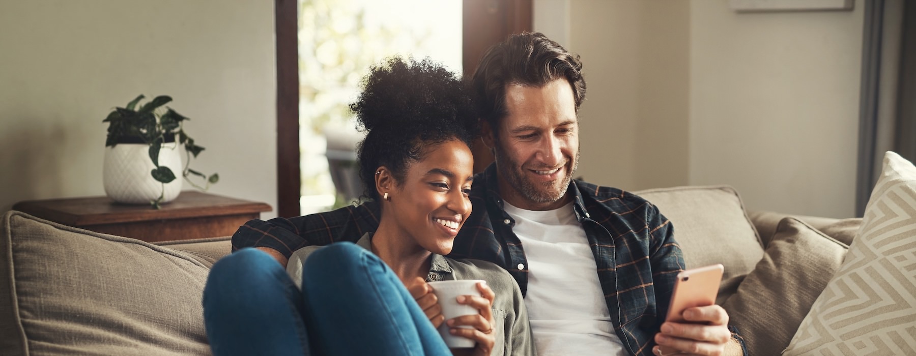 a man and woman sitting on a couch and looking at a cell phone