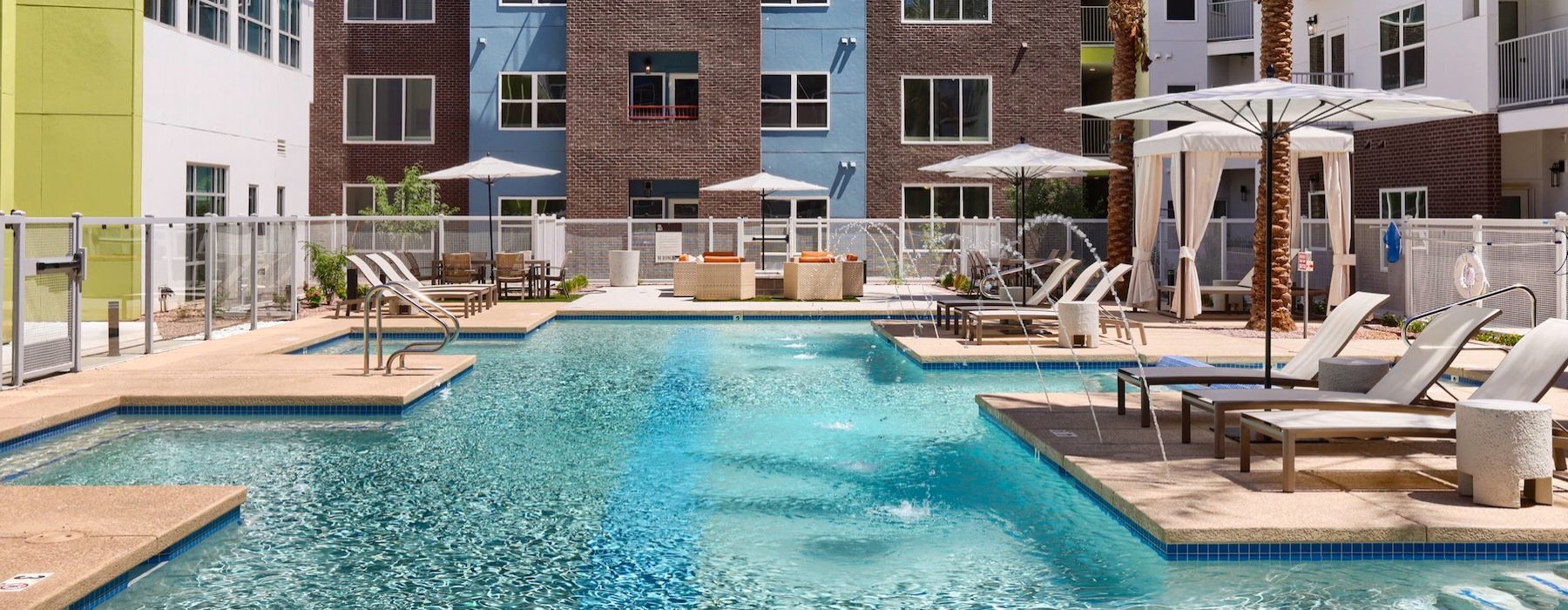 a pool with chairs and umbrellas by a building