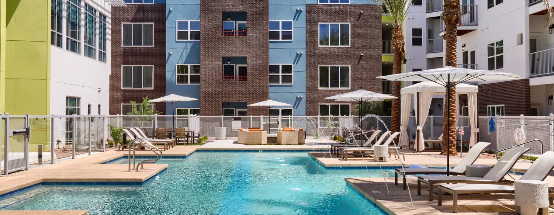 a pool with chairs and umbrellas by a building